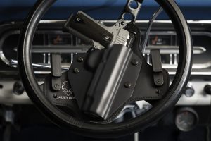 Gun in holster on car steering wheel