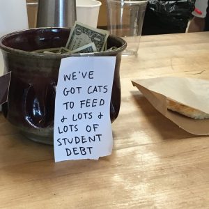 Tip jar with label reading "We've got cats to feed and lots of student debt." Image by tadhanna of Pixabay.